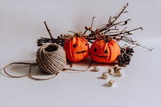 Decorative handcrafted pumpkins and pinecones placed on a plain surface