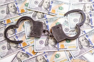 Handcuffs on the background of hundred-dollar bills. Illegal trade. Justice concept.