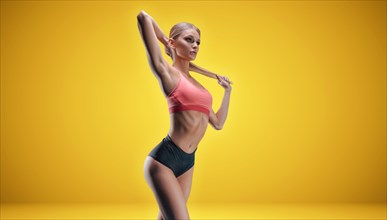 Charming tall girl posing in sportswear in the studio on a yellow background. The concept of a beautiful figure