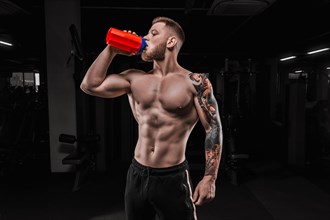 Portrait of an athlete drinking from a shaker in the gym. Bodybuilding and fitness concept.