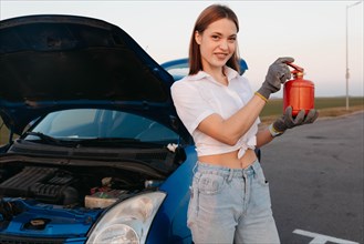 Young beautiful and hot woman driver holds a fire extinguisher in her hands