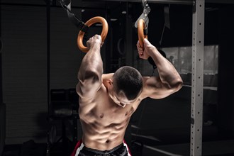 Athlete does warm-up on gymnastic rings. The concept of sport and healthy lifestyle.