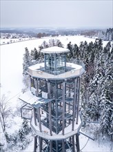 Aerial view of a lookout tower in a snowy forest landscape