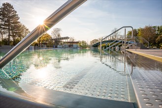 Swarm of sunbeams over a quiet swimming pool behind stainless steel railings