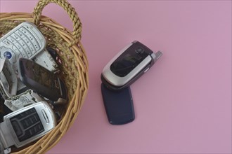 An open flip cell phone in the foreground with more phones in a basket behind
