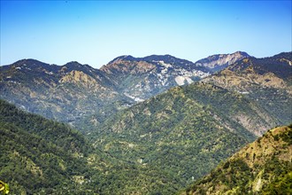 Vibrant mountain landscape under a clear blue sky with lush greenery in the Indian state of Uttarakhand