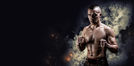 Portrait of a boxer of mixed martial arts standing on the background of smoke and fire. The concept of sports