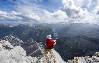 Mountaineer sitting on a rock on the summit of the Watzmann Mittelspitze