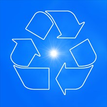 The universal recycling symbol. It is an internationally recognized symbol for recycling. Against blue sky and with the sun