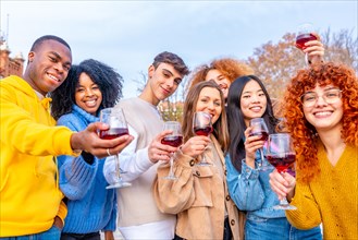 Students celebrating winter holidays with red wine in an urban park