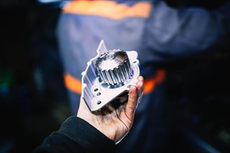 Automotive water pump of the engine cooling system in the hands of an auto mechanic