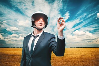 Portrait of a man in a helmet of a pilot. He stands in a field and launches a paper airplane. Business concept.