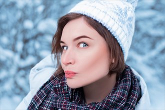 Beautiful model makes a funny surprised face. Winter forest. Warm clothes and Christmas shopping concept.