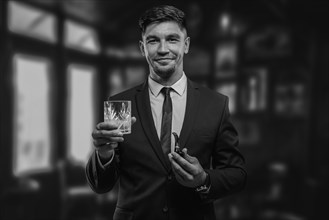 Portrait of an elegant man in a suit with a smoking pipe and a glass in a restaurant. Business concept.
