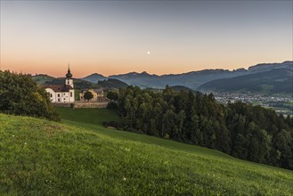 Church in the hamlet of Schlatt with a view of the Alpstein mountains with Hoher Kasten and the village of Appenzell at dusk