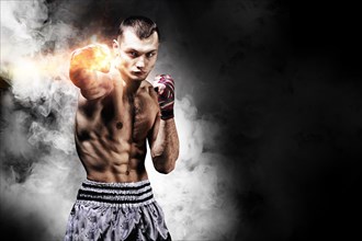 Thai boxer stands in the ring and punches in front of him. The concept of sports