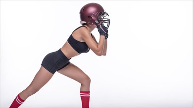 Woman in the uniform of an American football team player posing on a white background. Sports concept.