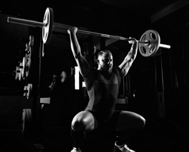 Weightlifter does an exercise with a barbell. Barbell above the head
