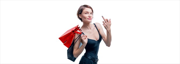 Portrait of a beautiful woman with red packages. She shows a fuck sign and smiles. Shopaholic concept. Shopping centers. Sales.