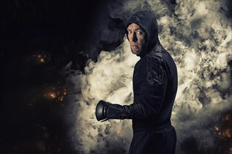 Mixed martial artist goes to battle in a sweatshirt amid fire and smoke. Concept of mma