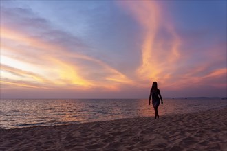Woman walking on the beach in the evening