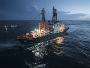 Offshore drilling ship during twilight with a dark blue ocean backdrop
