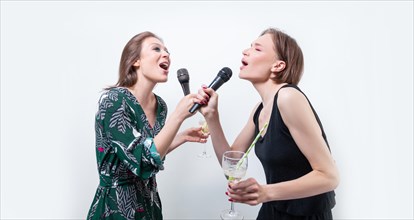 Portrait of two singing girls with glasses in their hands. Karaoke concept.