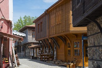 View into an alley with traditional wooden buildings and souvenir shops under a clear blue sky