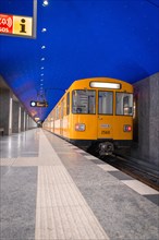 Yellow underground train at an empty platform at night