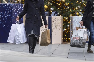 Christmas shopping at Outletcity Metzingen. Consumer tourists lug shopping bags. Factory outlet with around 80 shops of premium and luxury brands specialising in clothing