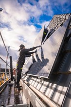 Reba worker mounts a solar panel on a roof with safety equipment