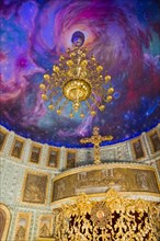 An opulent chandelier in a church with an illusionistic galaxy painted on the ceiling