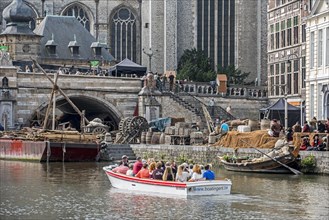 Tourists in boat look at background actors on filmset in Ghent