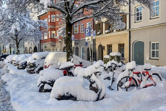 Snow-covered cars and bicycles with fresh snow
