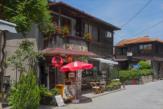Souvenir shop with cosy seating and red parasol in front of a traditional house with flowers