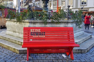 Red bench at the Christmas town hall fountain with imprint -no violence against woman-