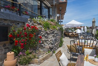 Inviting restaurant with terrace and blooming roses on a stone wall under a blue sky