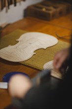 Unrecognizable luthier lute maker artisan in his workshop performing purfling process in a new raw classic handmade violin