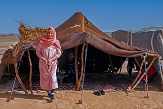 Nomadic Bedouin woman with hijab and man serving tea in tent in the Sahara Desert near Merzouga