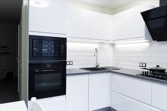 Interior of a white modern minimalist kitchen with kitchen electrical appliances