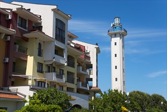 White lighthouse at a hotel complex under a clear blue sky