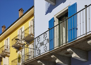 Forged balcony balustrade on colourful facades with windows and shutters in Ascona