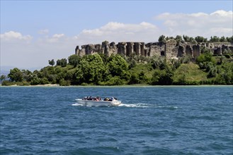 Boat with tourists in front of the Grottoes of Catullus
