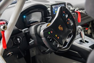 View into cockpit with digital display digital display modern steering wheel sports steering wheel of racing car racing version of Porsche Cayman GT4 Clubsport with in the centre logo coat of arms of ...