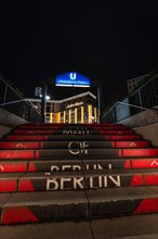 Entrance to a subway station at night with illuminated stairs with 'Berlin' written on them
