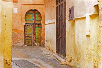 Moorish decorated door in alley of the old historic yellow medina of the city Meknes