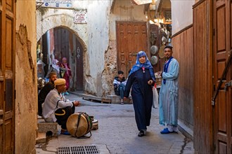 Moroccans wearing traditional kaftans in alley of medina in the city Fes