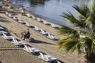 Early in the morning on the sandy beach of Kusadasi. The sunbeds are being prepared