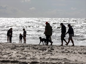 Walker with dog and family with children families on a beach at the North Sea in Vejers