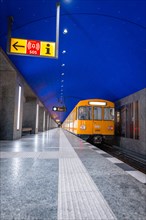 Yellow underground train standing at night on an empty urban platform